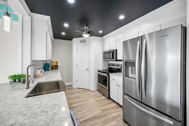 kitchen featuring recessed lighting, stainless steel appliances, a sink, white cabinetry, and light wood-style floors