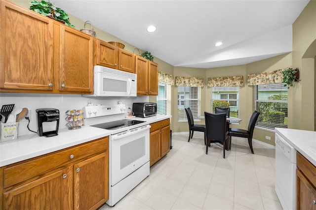 kitchen with white appliances, backsplash, and vaulted ceiling