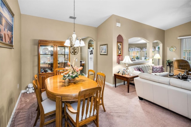 carpeted dining area with a chandelier