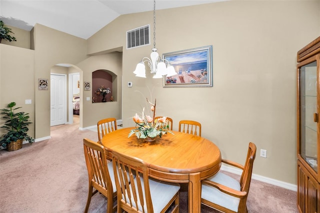 carpeted dining space with lofted ceiling and a notable chandelier