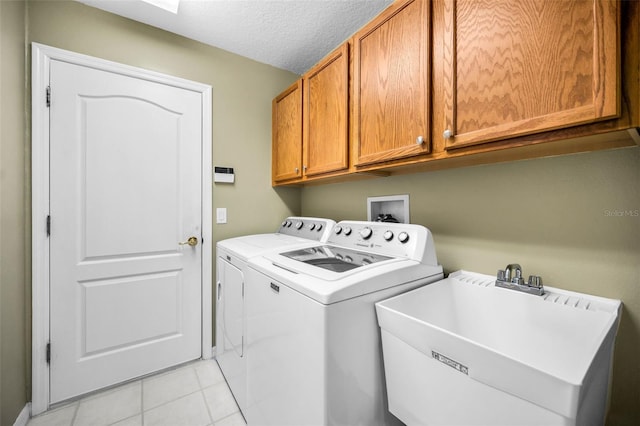 washroom featuring sink, cabinets, independent washer and dryer, a textured ceiling, and light tile patterned floors