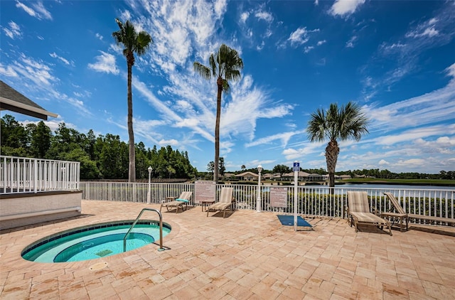 view of pool featuring a community hot tub, a patio, and a water view