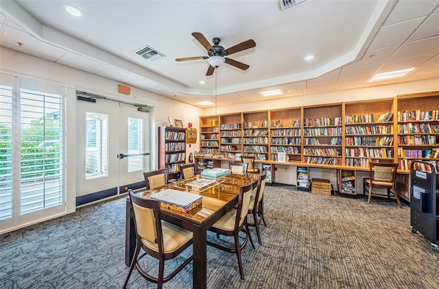 dining area featuring dark colored carpet, ceiling fan, french doors, and a tray ceiling