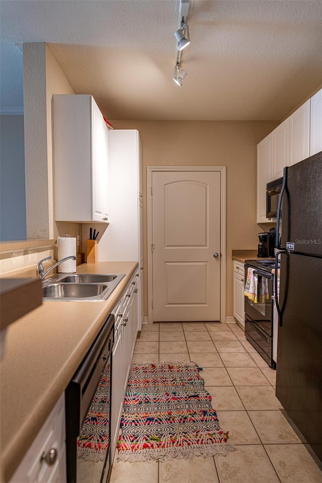 kitchen featuring track lighting, sink, black appliances, white cabinetry, and light tile patterned flooring