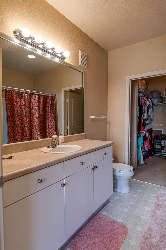 bathroom featuring a textured ceiling, vanity, and toilet