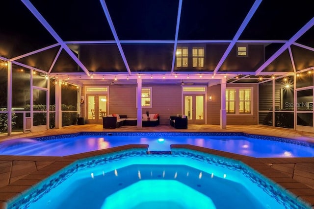 pool at twilight featuring an in ground hot tub, french doors, an outdoor living space, glass enclosure, and a patio