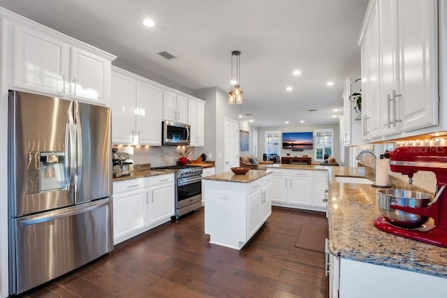 kitchen with a center island, sink, stainless steel appliances, kitchen peninsula, and decorative light fixtures