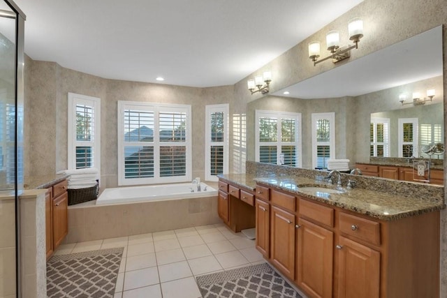 bathroom with tile patterned flooring, vanity, and tiled bath