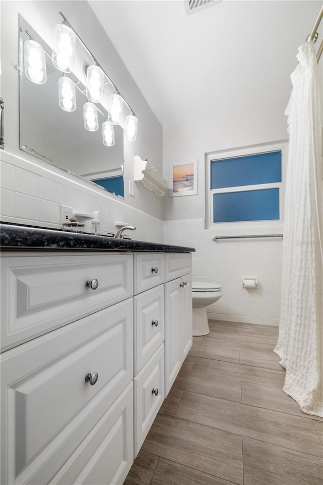 bathroom with vanity, visible vents, wood tiled floor, tile walls, and toilet