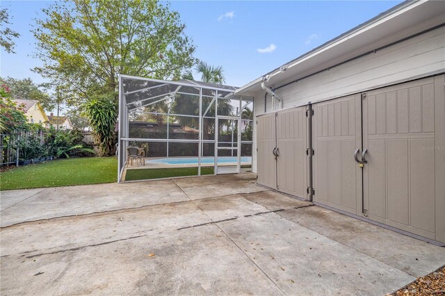 view of patio with glass enclosure, an outdoor pool, and fence