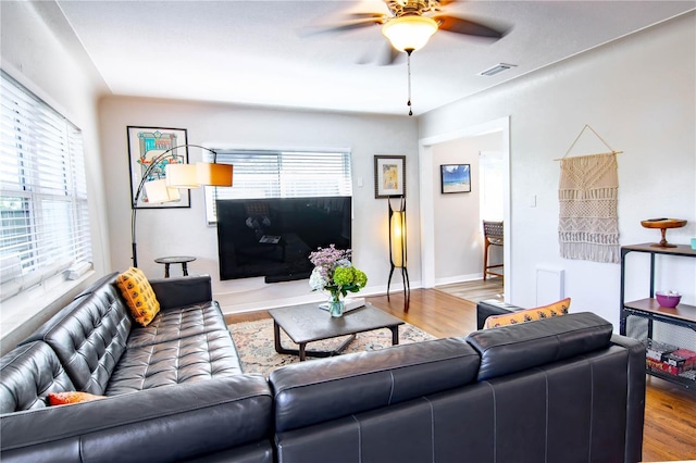 living room with visible vents, baseboards, wood finished floors, and a ceiling fan