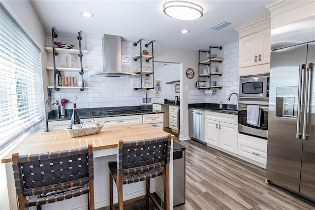 kitchen featuring visible vents, open shelves, wood counters, wall chimney exhaust hood, and built in appliances