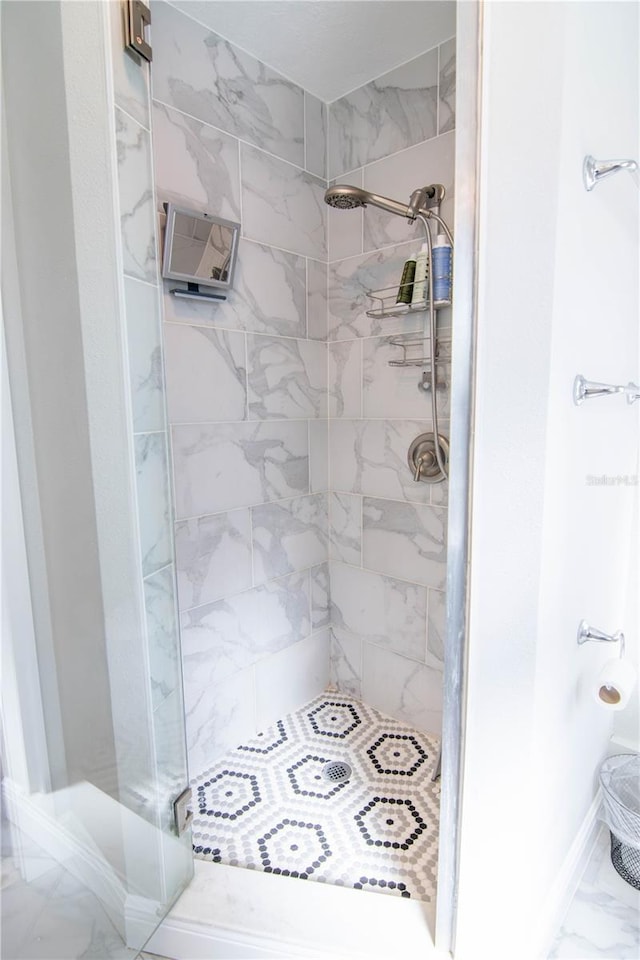 full bath with baseboards, a stall shower, and marble finish floor