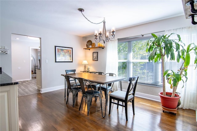 dining room featuring a chandelier, baseboards, and dark wood finished floors