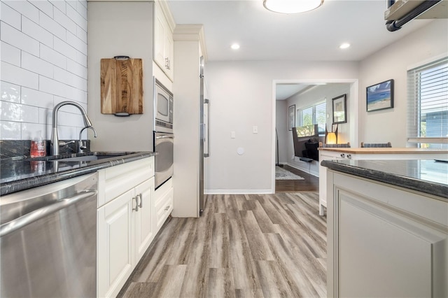 kitchen with dark stone counters, recessed lighting, a sink, appliances with stainless steel finishes, and light wood-type flooring