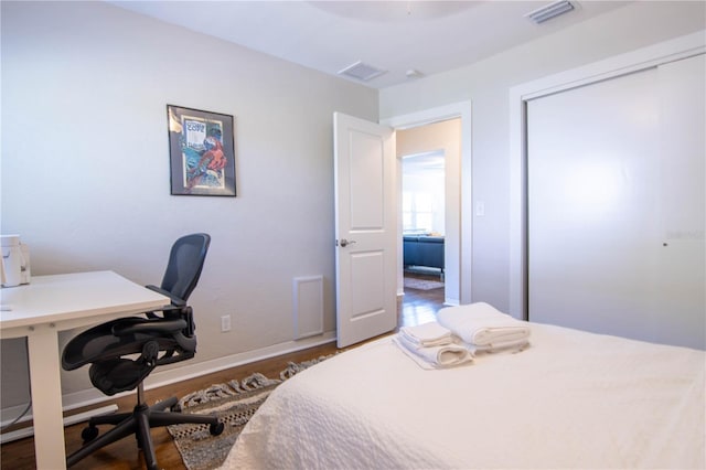 bedroom featuring a closet, visible vents, baseboards, and wood finished floors