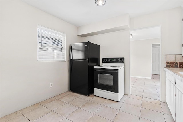 kitchen with black refrigerator, light tile patterned floors, electric range, and white cabinets