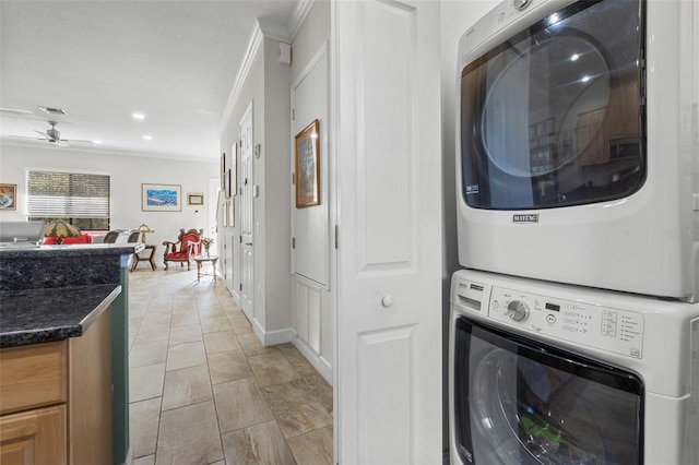 laundry area with ceiling fan, ornamental molding, and stacked washer and dryer