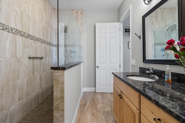 bathroom with a tile shower and vanity