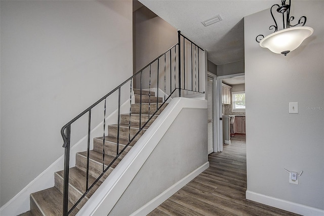 stairs with wood-type flooring and a textured ceiling