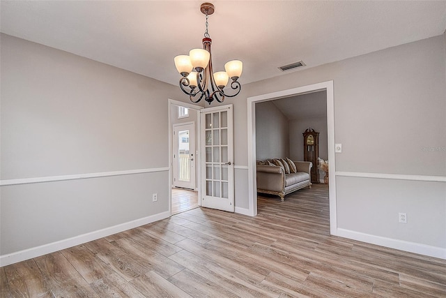 unfurnished dining area featuring hardwood / wood-style flooring and a notable chandelier