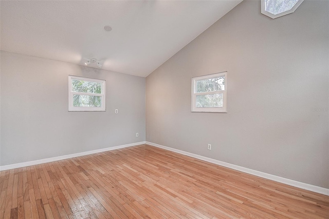 spare room with light hardwood / wood-style floors and vaulted ceiling