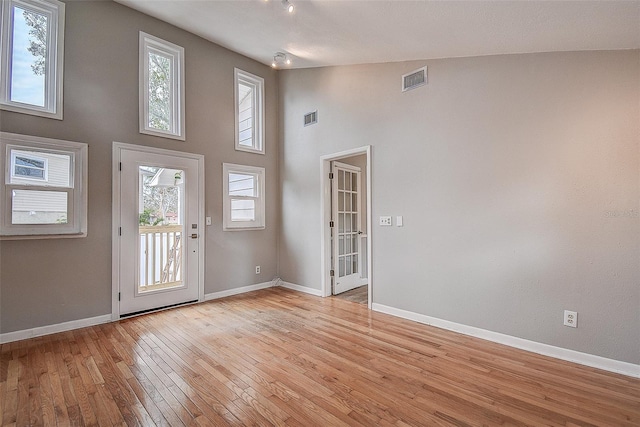 entryway featuring light hardwood / wood-style floors, a towering ceiling, and a healthy amount of sunlight