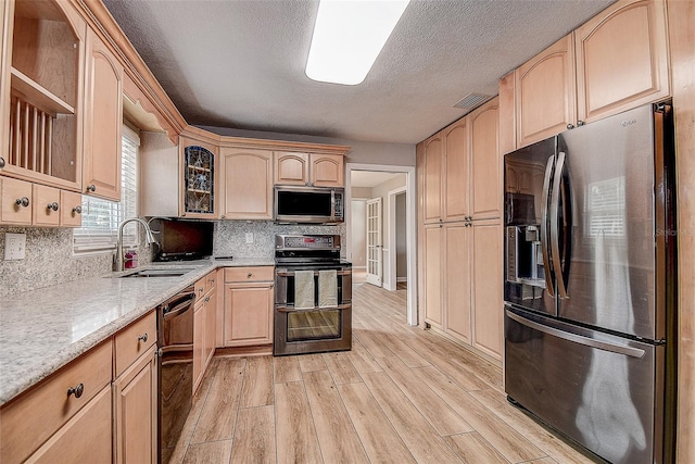 kitchen featuring light hardwood / wood-style floors, light brown cabinetry, backsplash, and appliances with stainless steel finishes