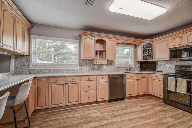 kitchen with light brown cabinets, stainless steel appliances, light hardwood / wood-style flooring, and sink