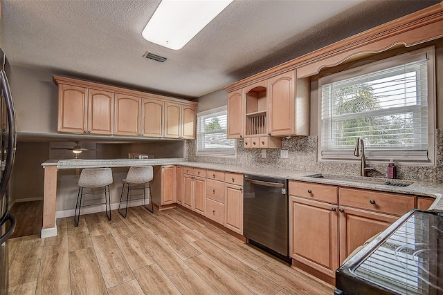 kitchen featuring light brown cabinetry, dishwasher, light wood-type flooring, and sink