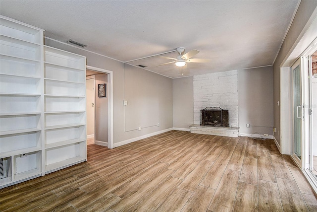 unfurnished living room with ceiling fan, a fireplace, wood-type flooring, and a textured ceiling