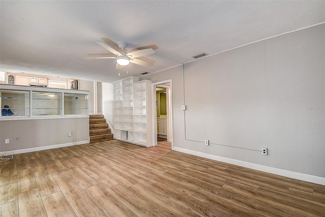 unfurnished room with ceiling fan, wood-type flooring, and built in shelves