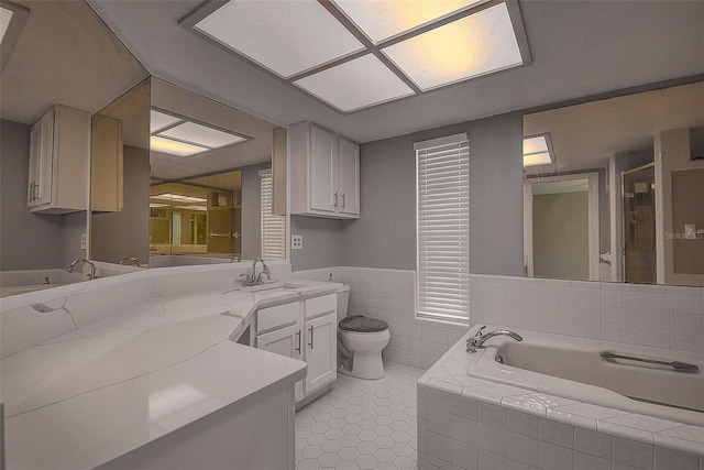 bathroom featuring tile patterned flooring, vanity, tiled bath, and toilet