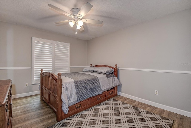 bedroom featuring ceiling fan, light hardwood / wood-style flooring, and a textured ceiling