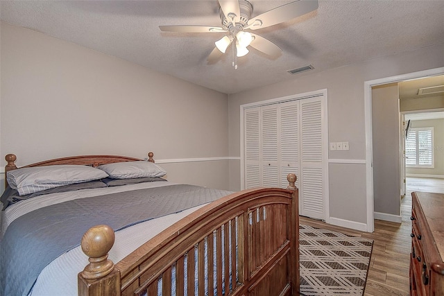 bedroom with hardwood / wood-style floors, a textured ceiling, a closet, and ceiling fan