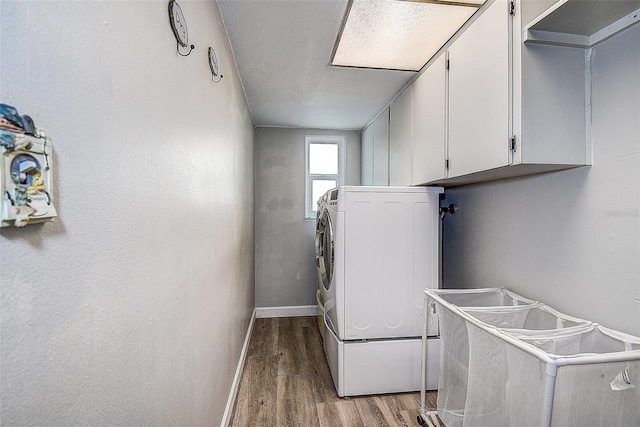 clothes washing area featuring cabinets, a textured ceiling, hardwood / wood-style flooring, and washer and dryer