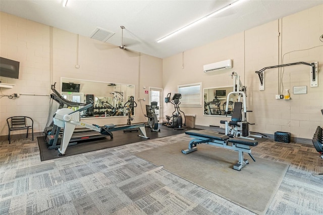 workout area featuring a wall mounted air conditioner and a towering ceiling