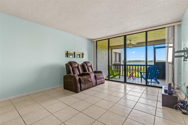 living room with ceiling fan, a wall of windows, a textured ceiling, and light tile patterned floors