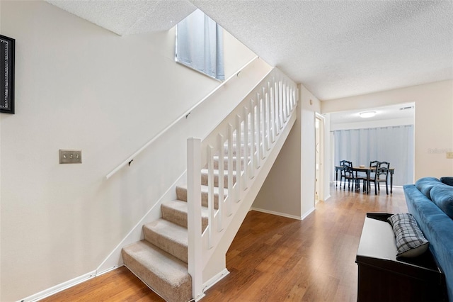 staircase featuring hardwood / wood-style floors and a textured ceiling