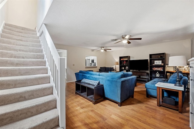 living room featuring ceiling fan, wood-type flooring, and a textured ceiling