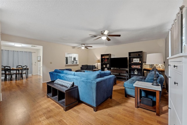 living room with ceiling fan, wood-type flooring, and a textured ceiling