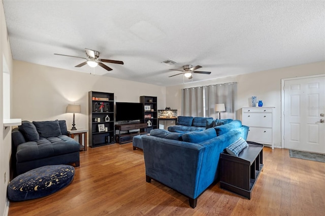 living room featuring ceiling fan, hardwood / wood-style flooring, and a textured ceiling