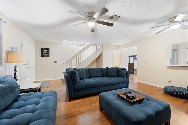 living room with hardwood / wood-style flooring, ceiling fan, and a textured ceiling