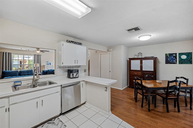 kitchen featuring sink, white cabinetry, a textured ceiling, stainless steel dishwasher, and kitchen peninsula