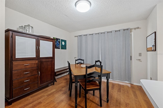 dining area with a textured ceiling and light wood-type flooring