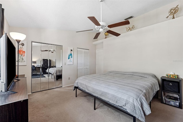 carpeted bedroom featuring multiple closets, ceiling fan, and a textured ceiling