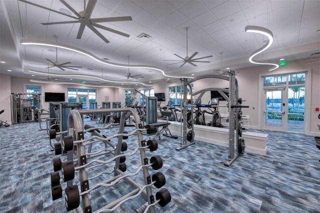 gym with ceiling fan, a raised ceiling, carpet floors, and french doors