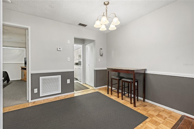 interior space with light parquet flooring, a textured ceiling, and an inviting chandelier