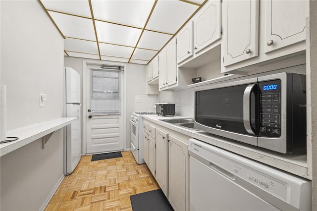 kitchen with light parquet floors, white cabinets, and white appliances