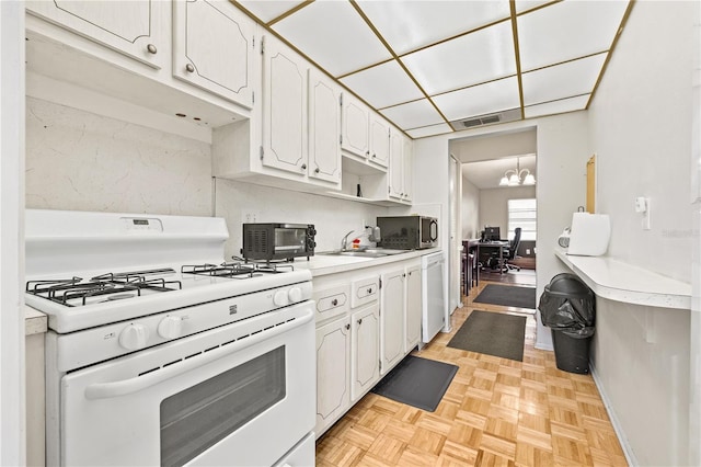 kitchen with an inviting chandelier, white cabinets, sink, white range with gas cooktop, and light parquet flooring